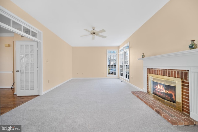 carpeted living room featuring a brick fireplace, a ceiling fan, and baseboards