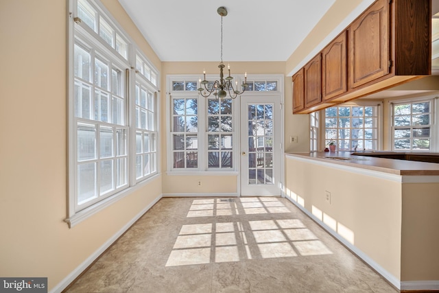 unfurnished dining area with a chandelier, a wealth of natural light, and baseboards