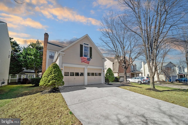 property exterior at dusk with a garage, driveway, a lawn, a residential view, and a chimney