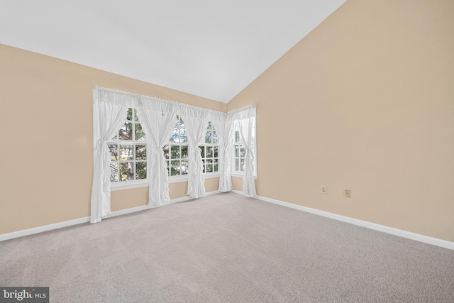 carpeted empty room featuring high vaulted ceiling and baseboards