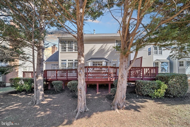 rear view of house featuring a chimney and a wooden deck