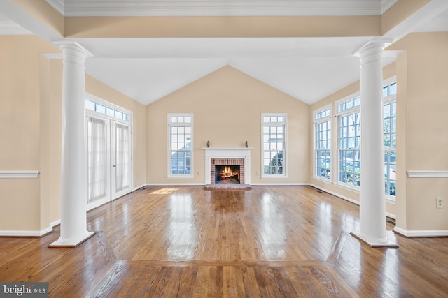 unfurnished living room with a healthy amount of sunlight, decorative columns, a fireplace, and wood finished floors