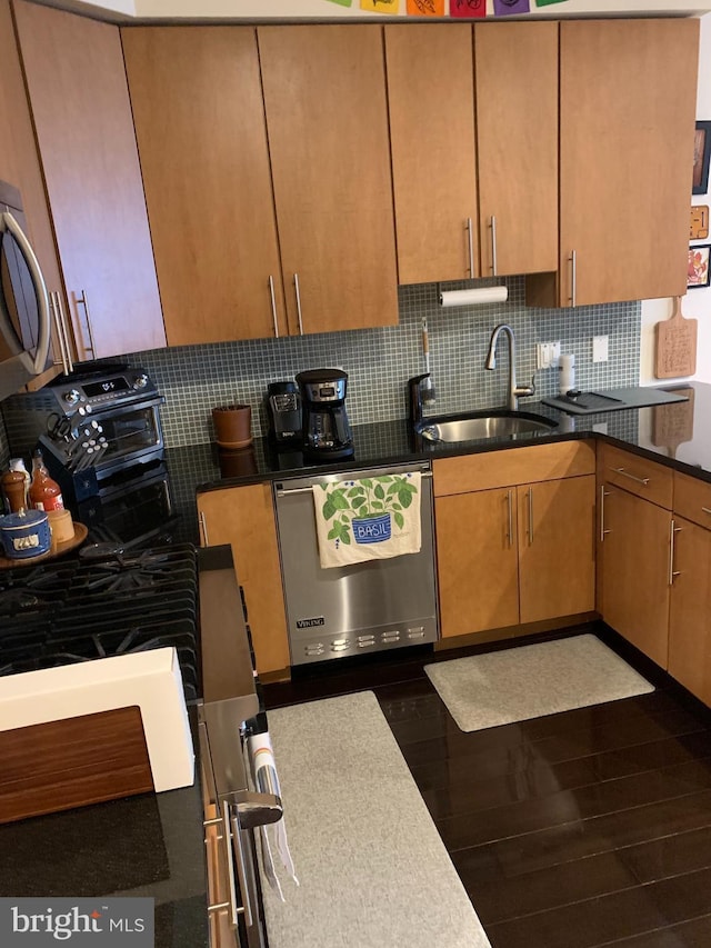 kitchen featuring sink, black range oven, dark wood-type flooring, stainless steel dishwasher, and backsplash