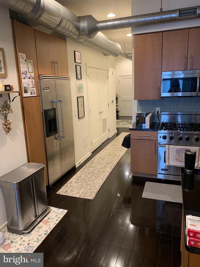 kitchen featuring backsplash, high quality appliances, and dark wood-type flooring