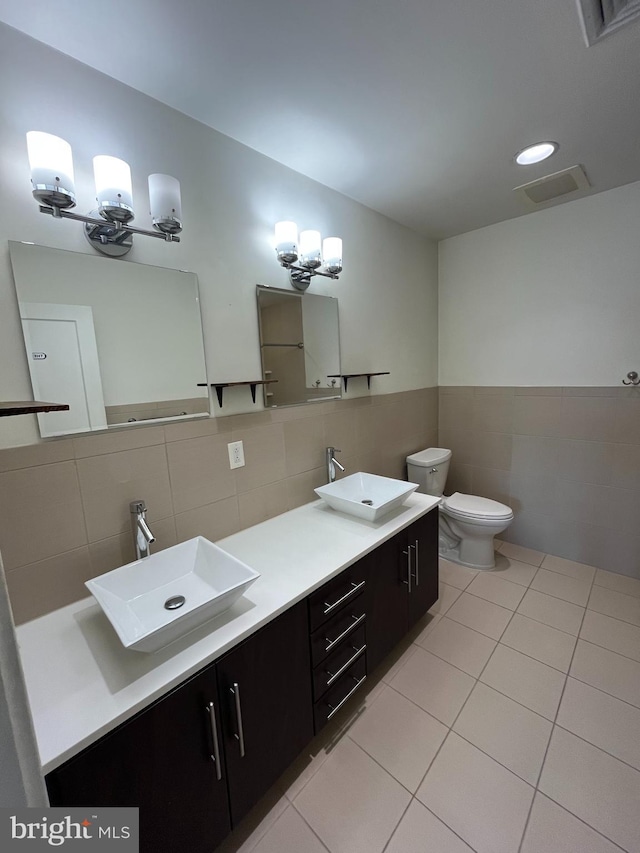 bathroom with tile patterned floors, vanity, tile walls, a notable chandelier, and toilet