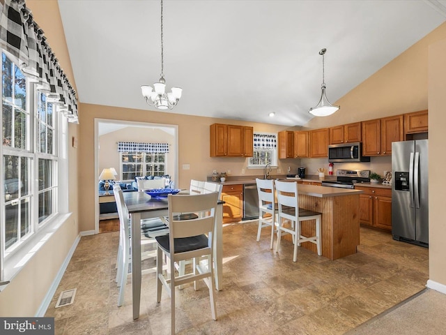 kitchen with a notable chandelier, a center island, stainless steel appliances, and decorative light fixtures