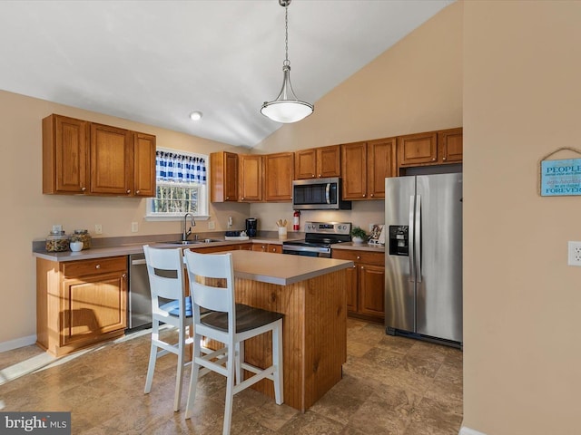 kitchen with a center island, lofted ceiling, hanging light fixtures, appliances with stainless steel finishes, and a breakfast bar area