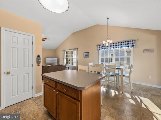 kitchen with pendant lighting, a kitchen island, an inviting chandelier, and vaulted ceiling