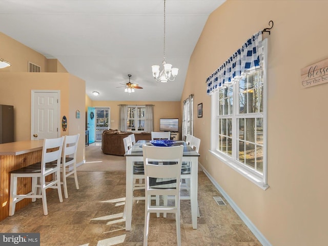 dining room featuring ceiling fan with notable chandelier and vaulted ceiling