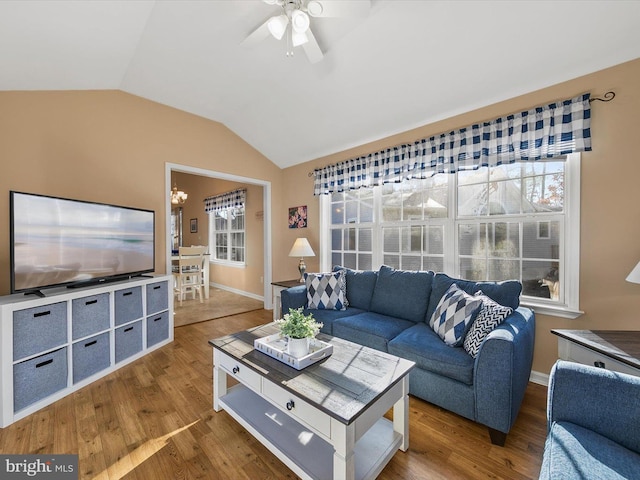 living room featuring hardwood / wood-style floors, ceiling fan with notable chandelier, and vaulted ceiling