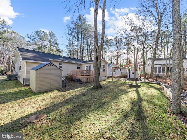 view of yard featuring a wooden deck and a storage shed