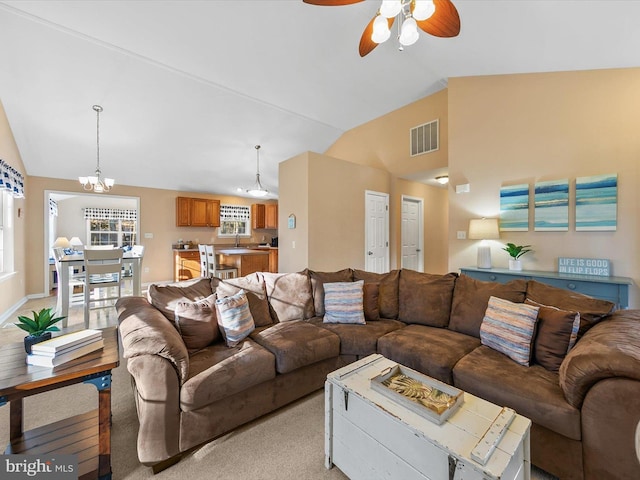 living room featuring ceiling fan with notable chandelier, light colored carpet, and vaulted ceiling