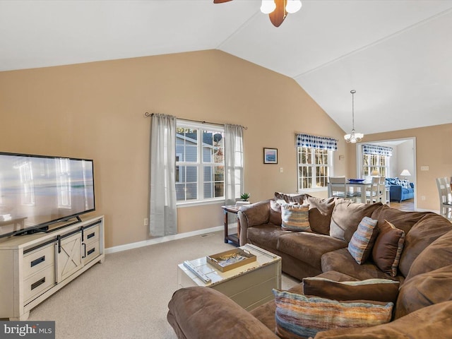 living room with ceiling fan with notable chandelier, plenty of natural light, light carpet, and vaulted ceiling