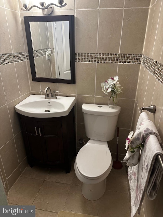 bathroom featuring vanity, toilet, and tile walls