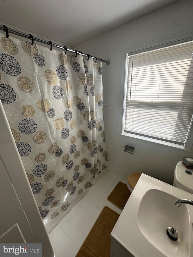 bathroom with tile patterned flooring, toilet, walk in shower, and sink