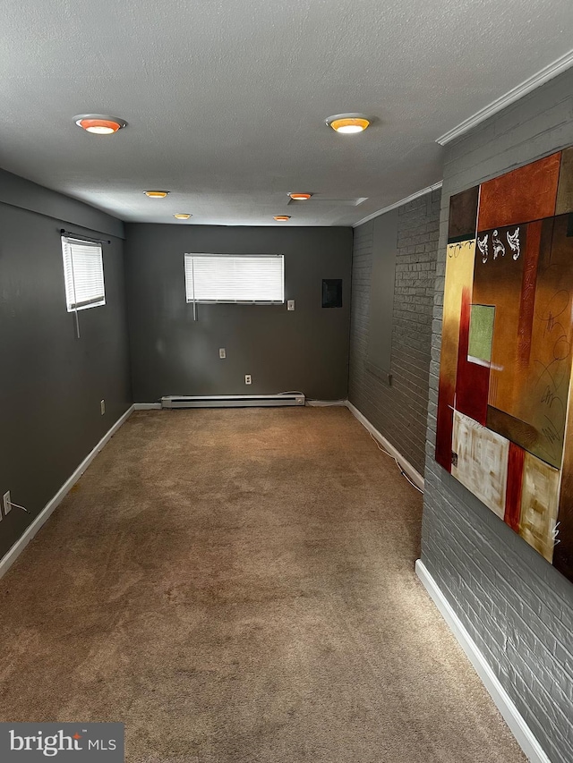 basement with baseboard heating, carpet floors, brick wall, and a textured ceiling