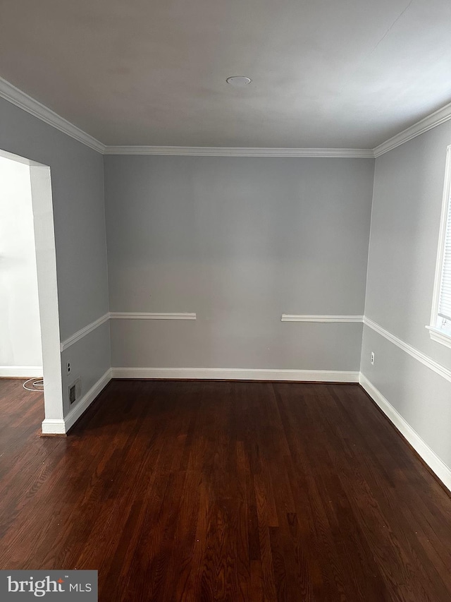 empty room featuring dark wood-type flooring and ornamental molding