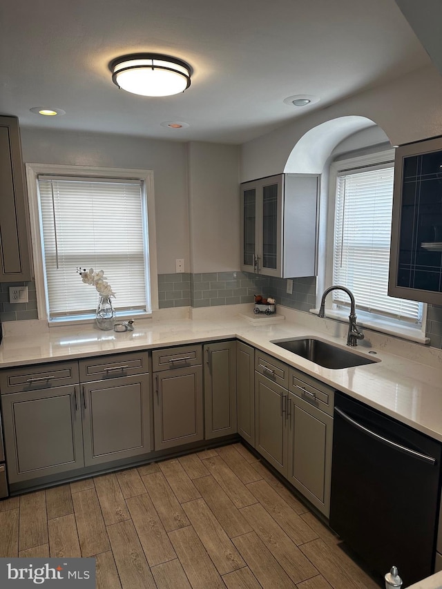 kitchen with tasteful backsplash, gray cabinets, sink, and black dishwasher