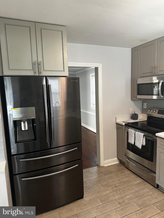 kitchen featuring stainless steel appliances, light hardwood / wood-style flooring, and gray cabinetry