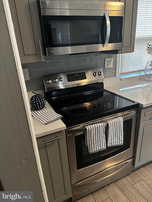 kitchen with gray cabinets, appliances with stainless steel finishes, and tasteful backsplash