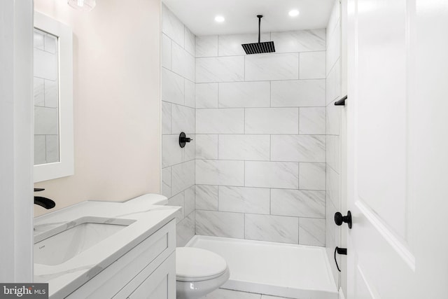 bathroom with vanity, toilet, and a tile shower