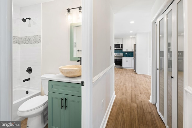 full bathroom with hardwood / wood-style floors, vanity, backsplash, shower / washtub combination, and toilet