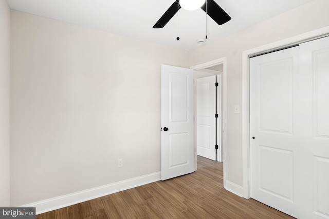 unfurnished bedroom featuring ceiling fan, a closet, and wood-type flooring