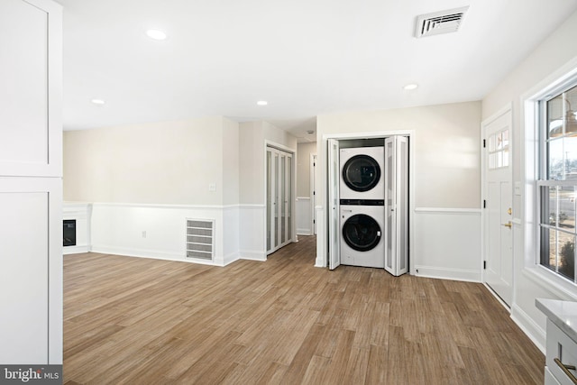 clothes washing area with light wood-type flooring and stacked washer and dryer