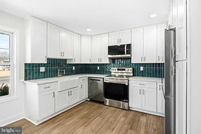 kitchen featuring white cabinets, appliances with stainless steel finishes, light hardwood / wood-style flooring, and sink