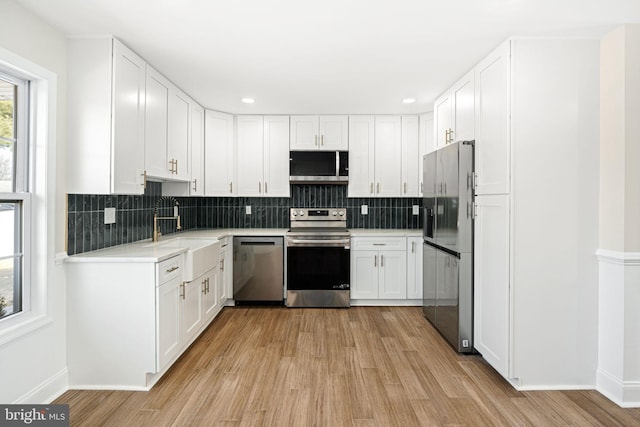 kitchen with white cabinets, light hardwood / wood-style floors, sink, and stainless steel appliances