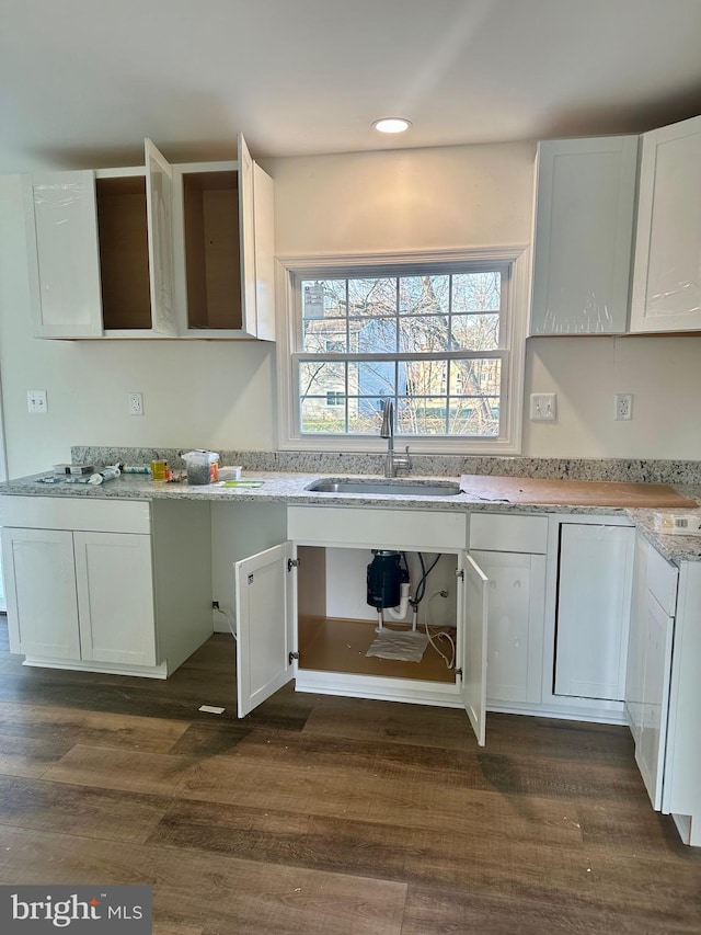 kitchen featuring light stone countertops, sink, white cabinets, and dark hardwood / wood-style flooring