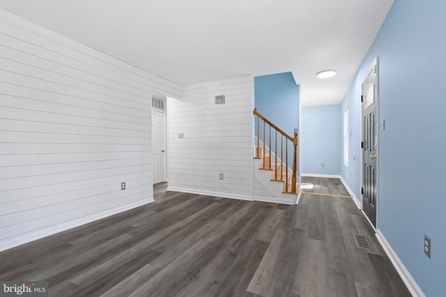 interior space with wood walls and dark wood-type flooring