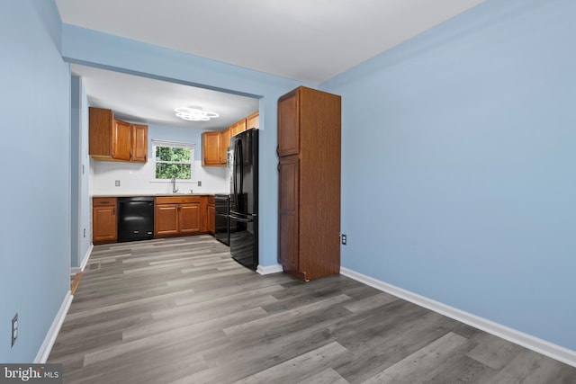 kitchen featuring light hardwood / wood-style flooring, black appliances, and sink