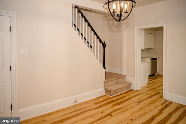 stairway with hardwood / wood-style flooring and a notable chandelier