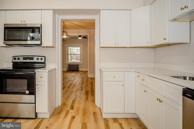 kitchen featuring white cabinets, stainless steel appliances, and radiator