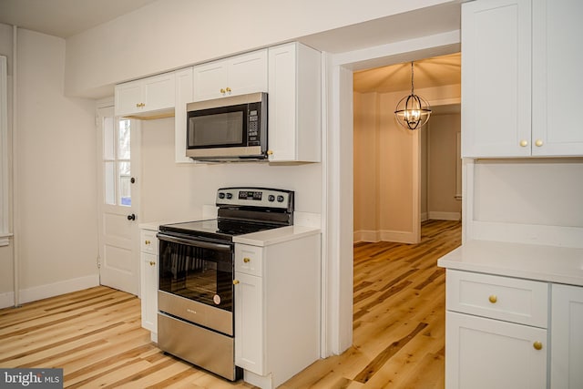 kitchen with appliances with stainless steel finishes, an inviting chandelier, white cabinetry, and hanging light fixtures