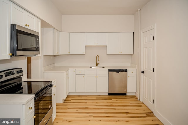 kitchen featuring sink, white cabinets, stainless steel appliances, and light hardwood / wood-style flooring