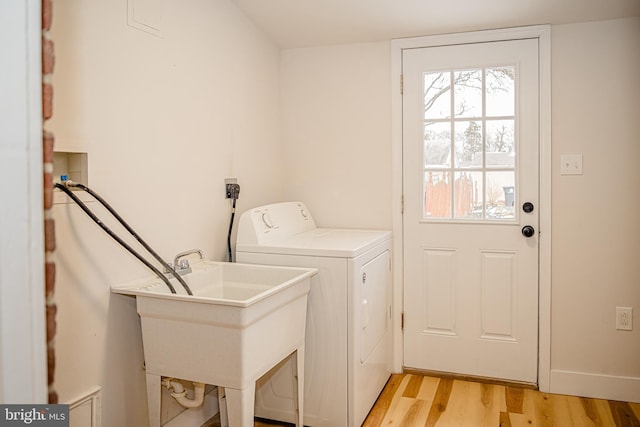 laundry area with washer / clothes dryer, sink, and light hardwood / wood-style floors