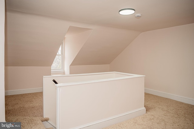 additional living space featuring light colored carpet and vaulted ceiling