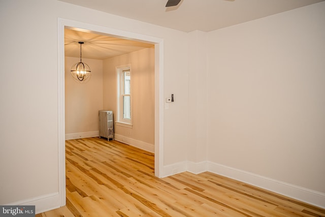 spare room featuring radiator heating unit, an inviting chandelier, and wood-type flooring