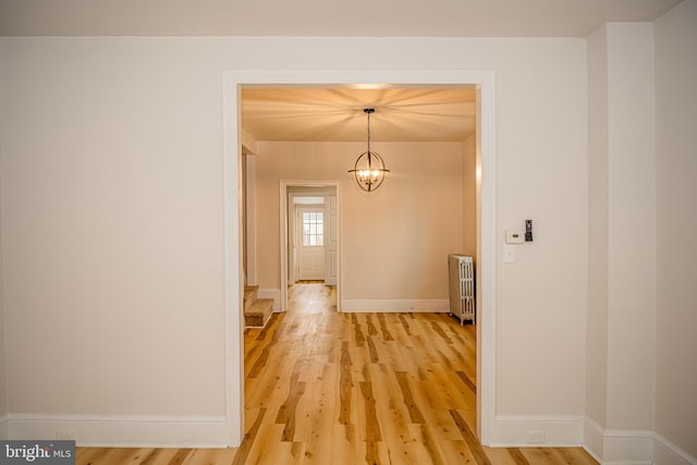 corridor featuring hardwood / wood-style flooring, radiator heating unit, and a chandelier