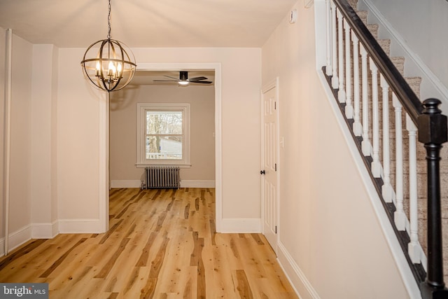 interior space with ceiling fan with notable chandelier, light hardwood / wood-style floors, and radiator