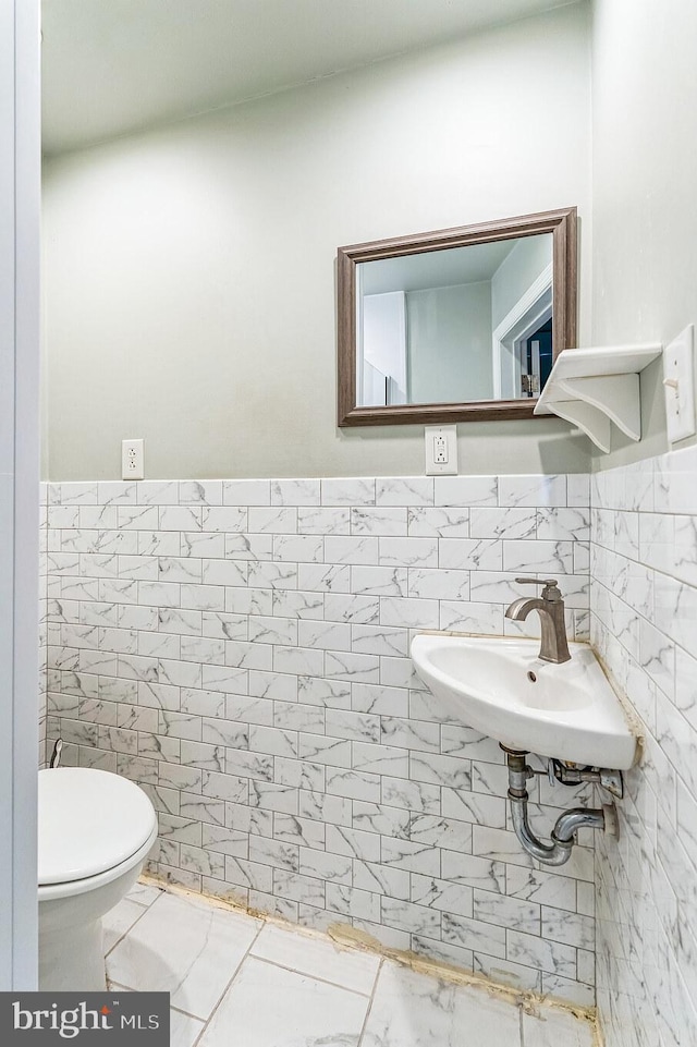 bathroom with tile patterned floors, sink, tile walls, and toilet