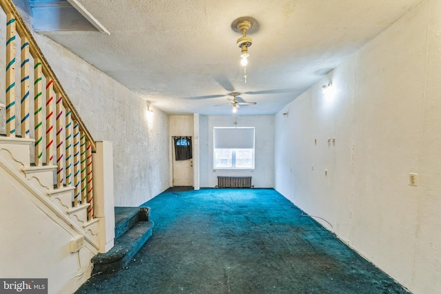 unfurnished living room with ceiling fan, radiator heating unit, carpet floors, and a textured ceiling