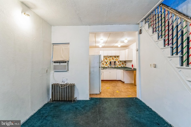 interior space with radiator, cooling unit, dark carpet, and a textured ceiling