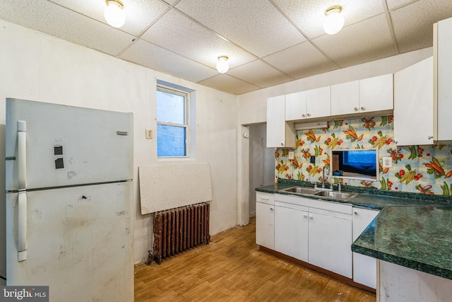 kitchen featuring radiator, white cabinets, white refrigerator, sink, and light hardwood / wood-style flooring