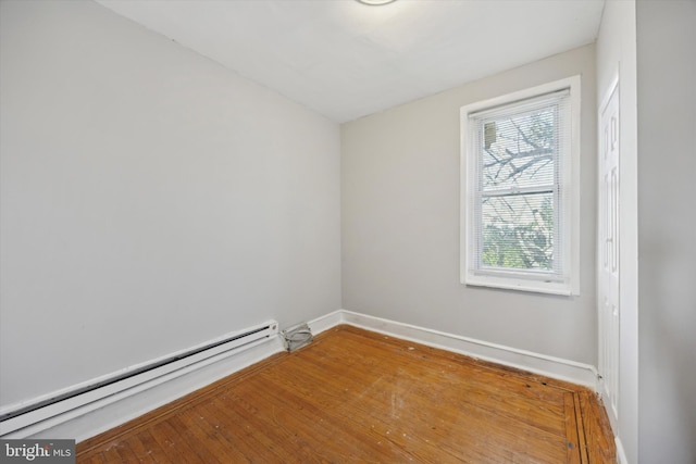 unfurnished room featuring hardwood / wood-style flooring and a baseboard radiator