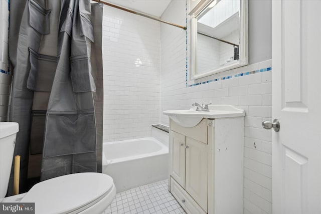 full bathroom featuring tile patterned floors, toilet, vanity, tile walls, and tiled shower / bath