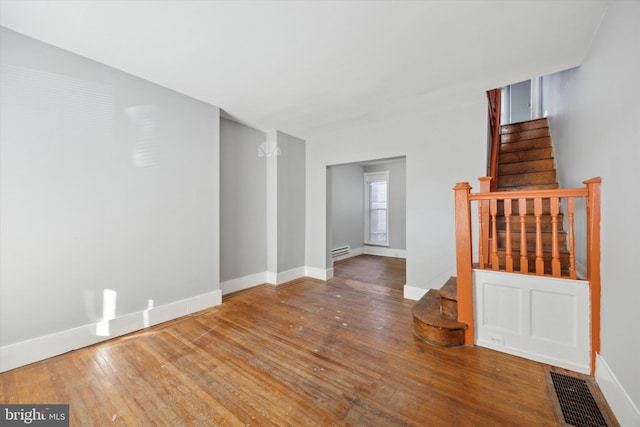 unfurnished living room featuring wood-type flooring and baseboard heating