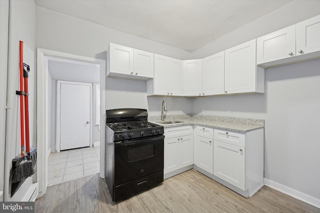 kitchen featuring white cabinets, sink, light hardwood / wood-style floors, light stone counters, and black range with gas cooktop